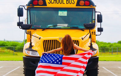 exchange student con bandiera americana davanti al bus giallo