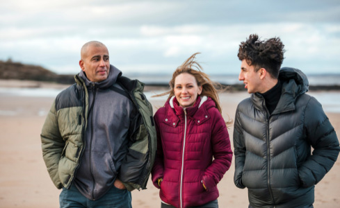 Host parents with exchange student at beach in fall