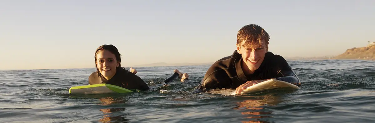 Ragazzi durante l'anno all'estero che fanno surf in mare in destinazioni come America e australia